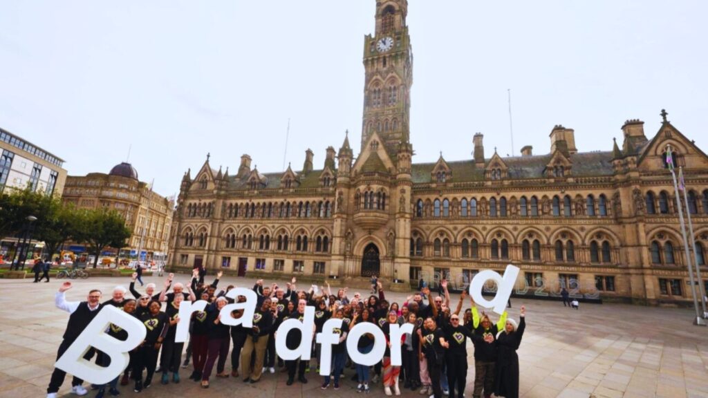 A group of people holding large letters spelling “Bradford” in front of Bradford City Hall, celebrating the city’s UK City of Culture status for Bradford 2025.
